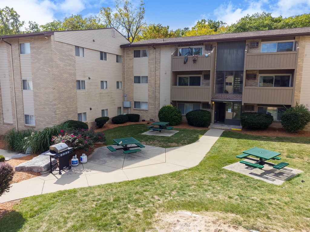 Apartment complex with a green lawn and picnic tables.