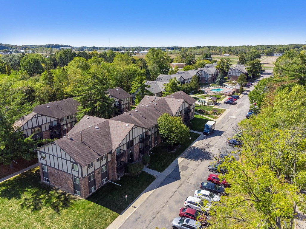 A sunny day at a residential area with houses and cars parked on the street.