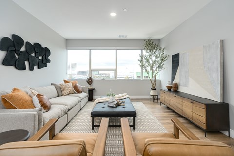A modern living room with a grey sofa, a black coffee table, and a large abstract painting on the wall.