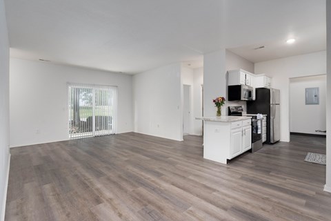 A spacious kitchen with white cabinets and a wooden floor.