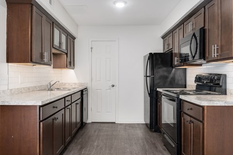 A kitchen with dark wood cabinets and a black refrigerator.