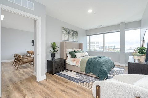 A bedroom with a bed, a chair, and a plant.