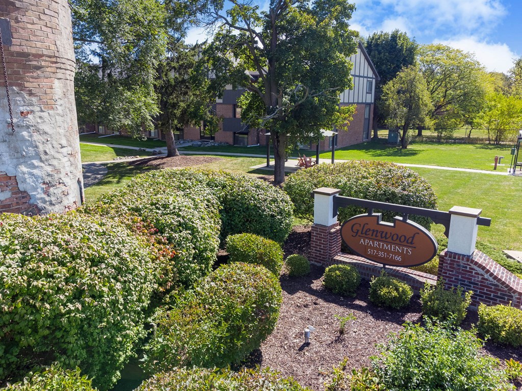 A sign for Glenwood Apartments is surrounded by green bushes.