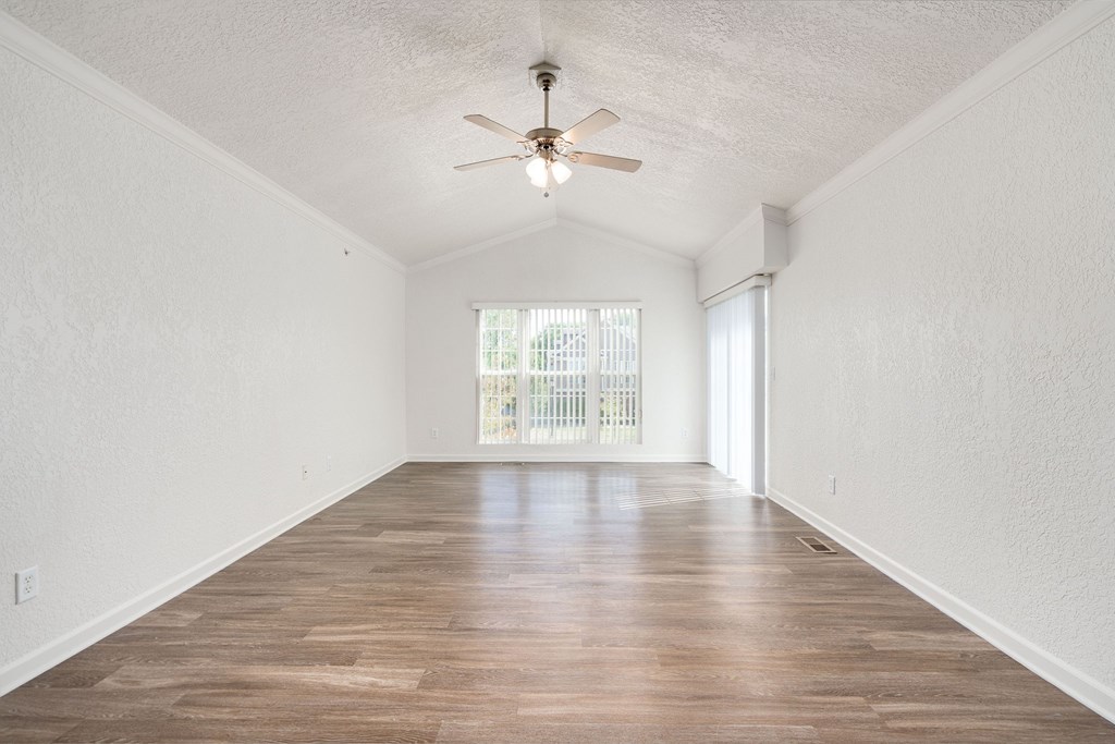A room with a ceiling fan and wooden flooring.