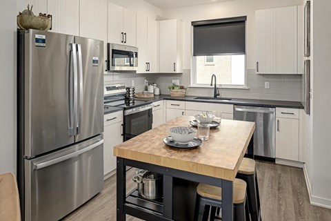 A modern kitchen with a wooden table set for two.