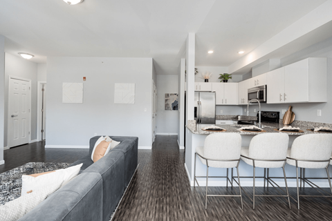 A modern kitchen with white cabinets and a grey couch.