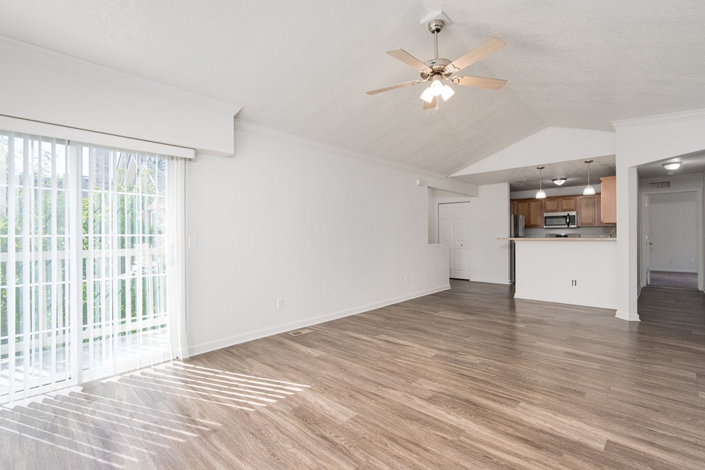 A room with a ceiling fan and wooden flooring.