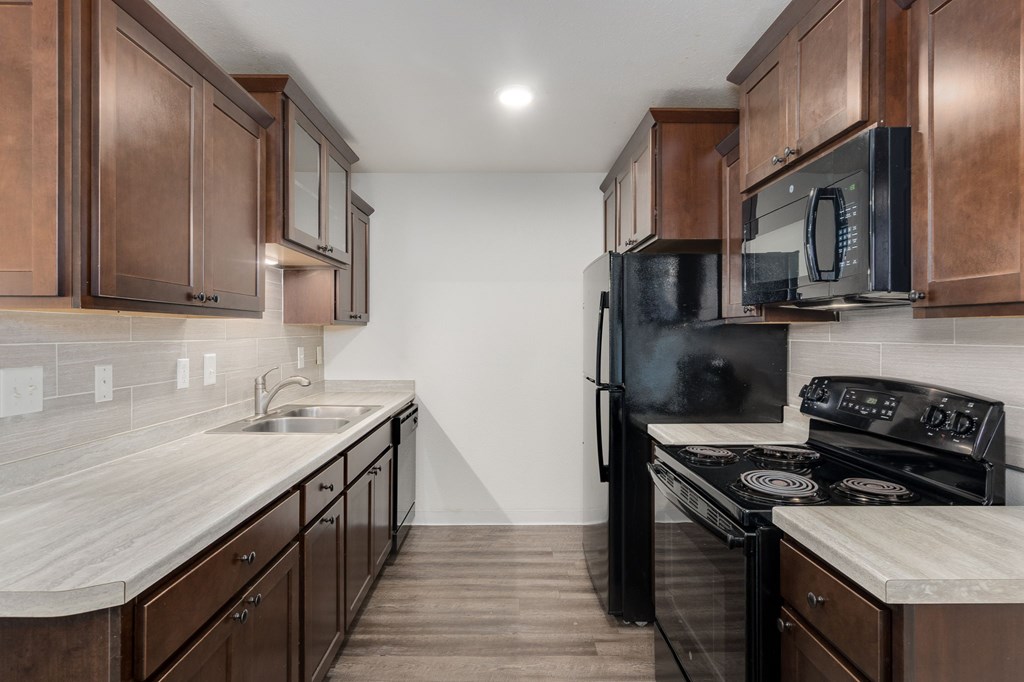 A kitchen with brown cabinets and a black refrigerator.