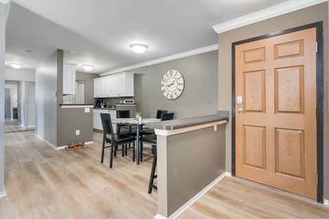 A kitchen with a table and chairs and a clock on the wall.
