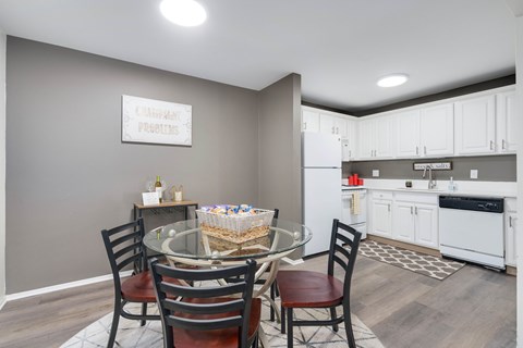 A kitchen with a dining table and chairs in front of it.