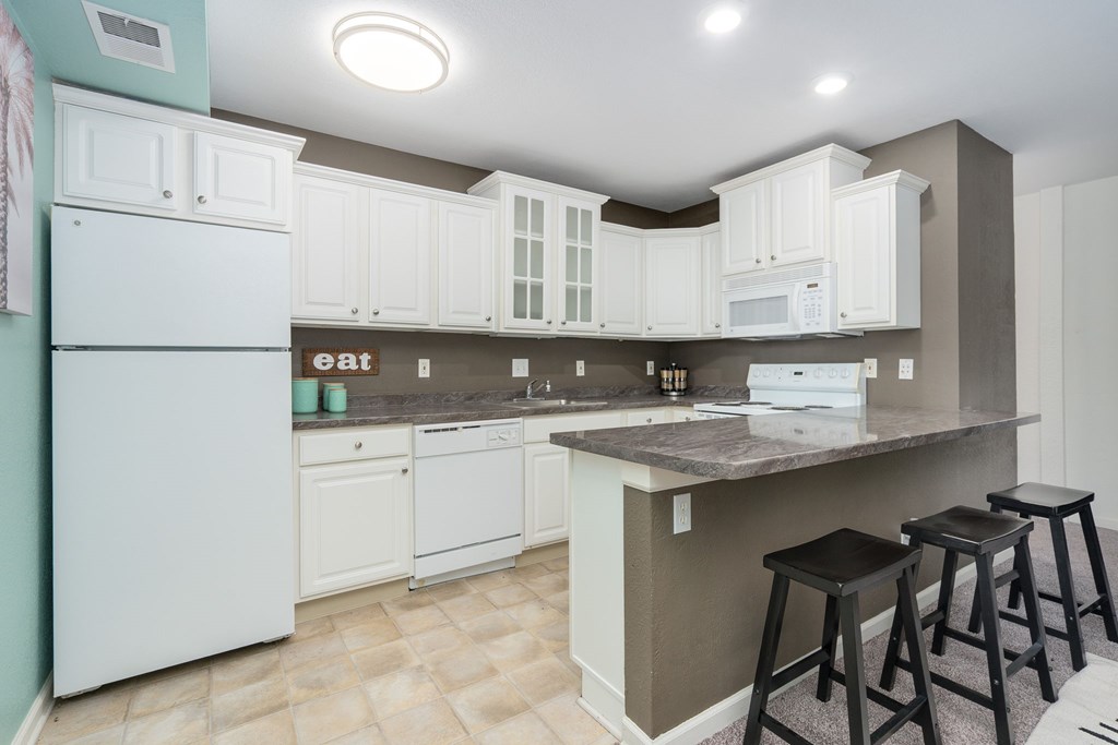 A kitchen with white cabinets and a white fridge.
