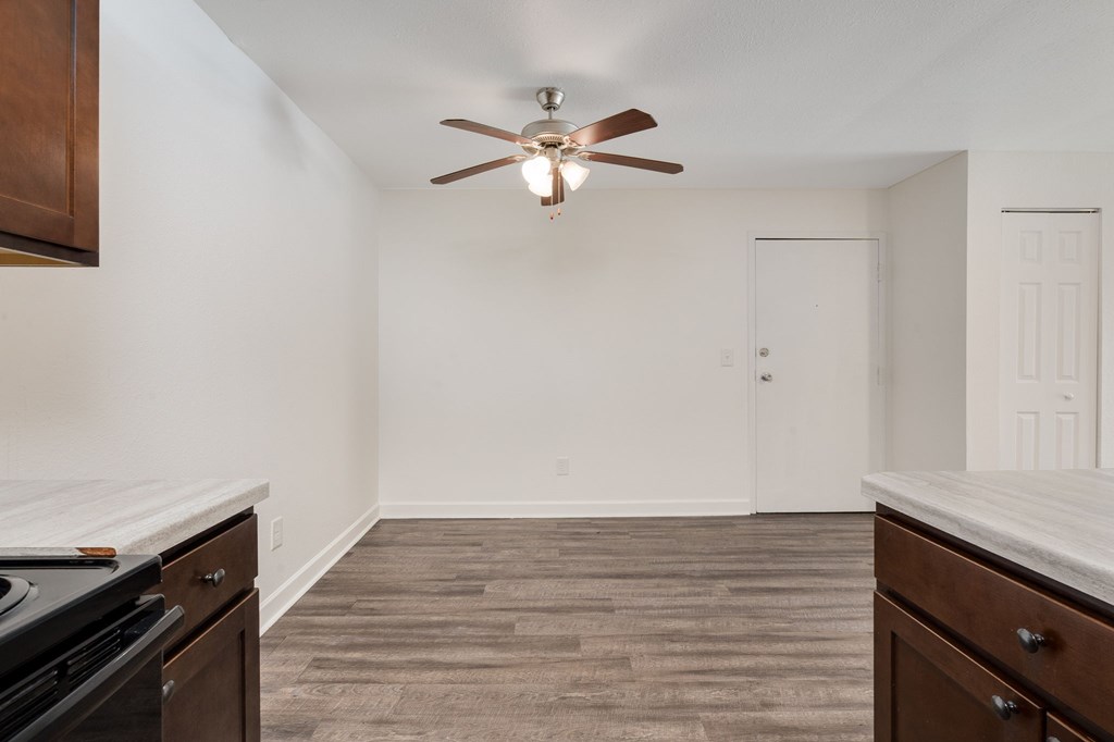 A room with a ceiling fan and wood flooring.