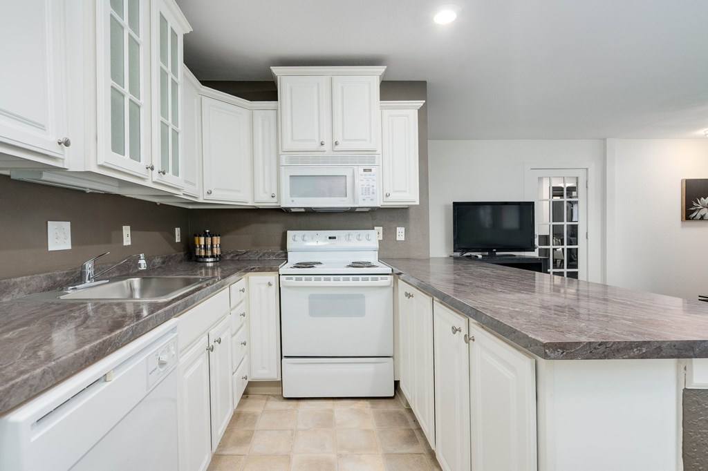 A kitchen with white cabinets and a granite countertop.