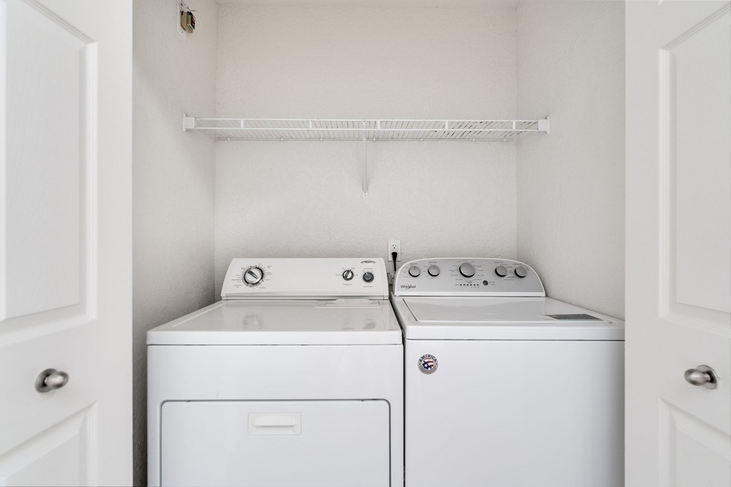 Two white washing machines in a small laundry room.