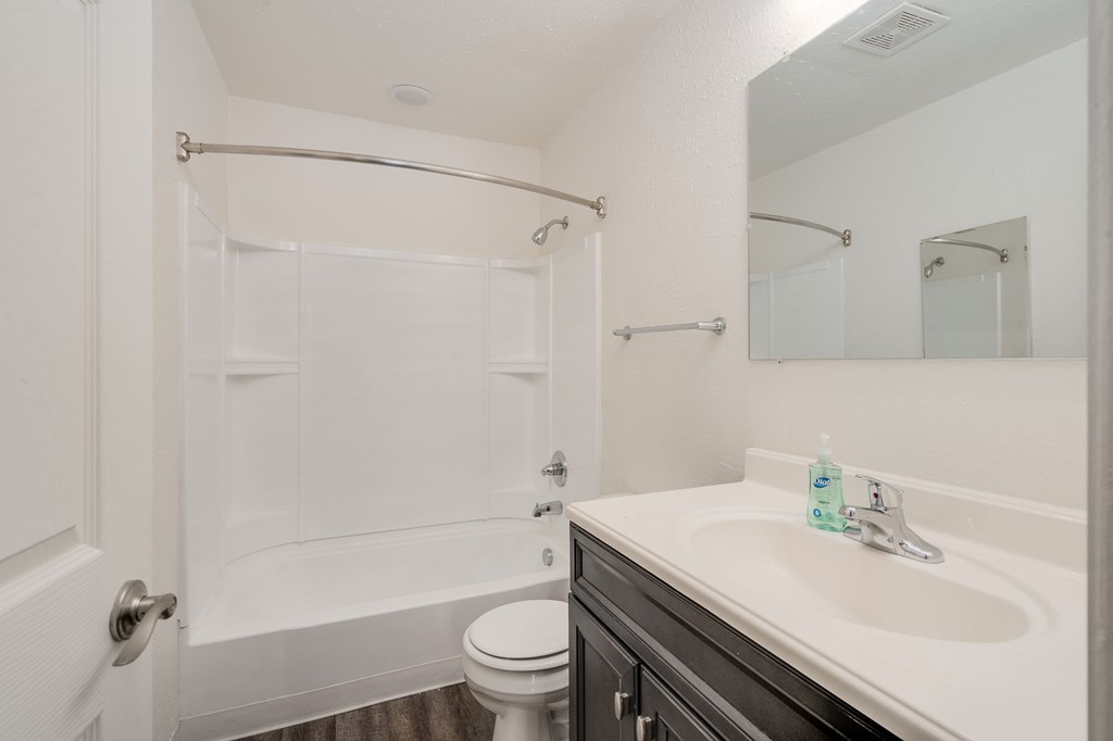 A white bathroom with a toilet, sink, and shower.