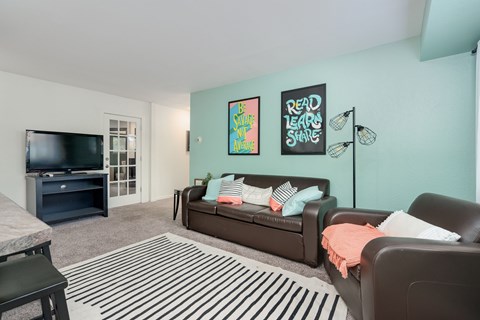 A living room with a brown couch and a striped rug.