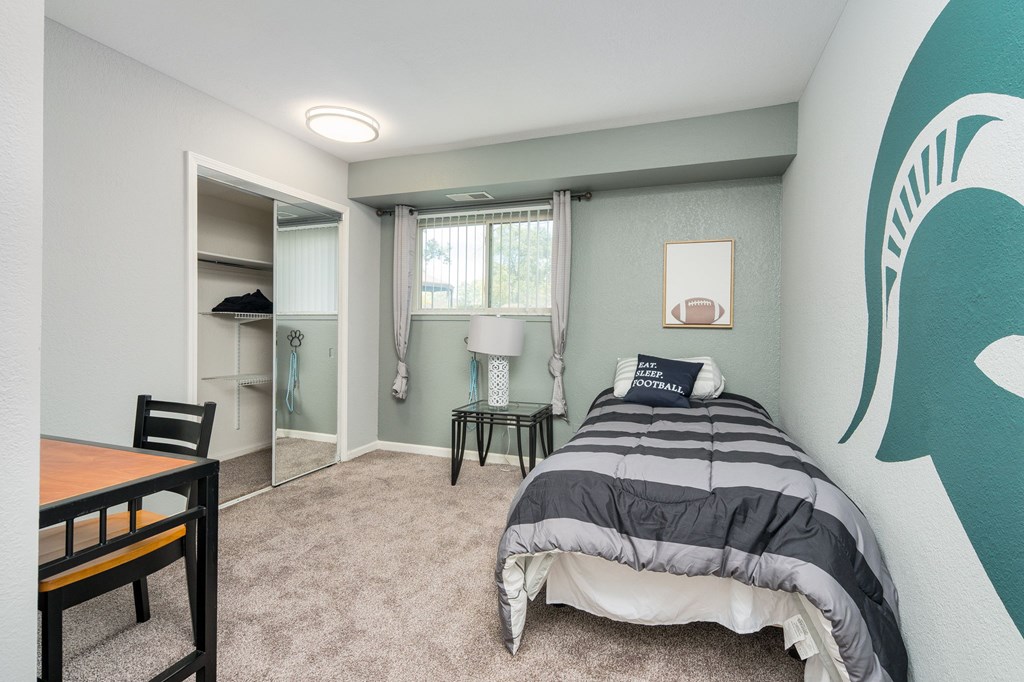 A bedroom with a bed, a chair, and a desk.
