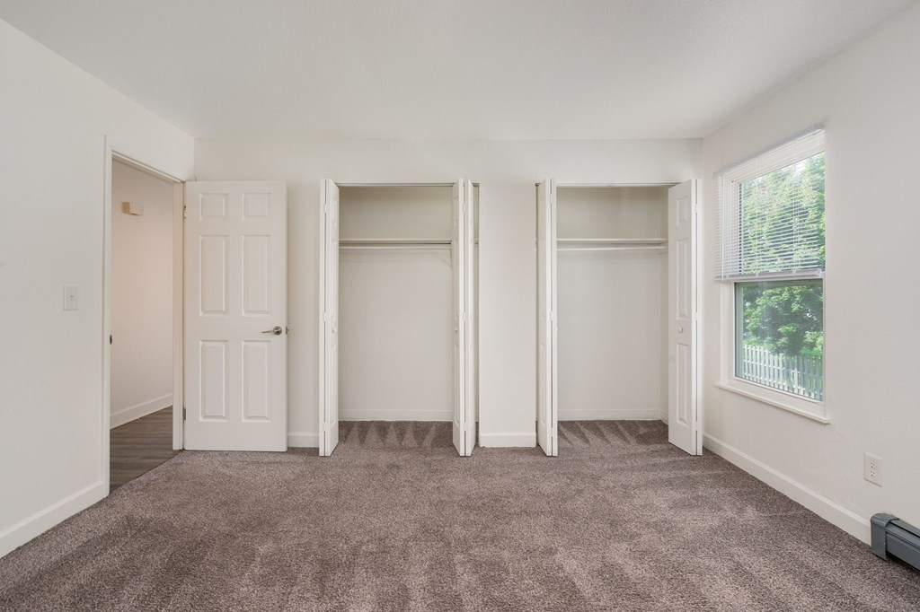 A room with a carpeted floor and a window with blinds.
