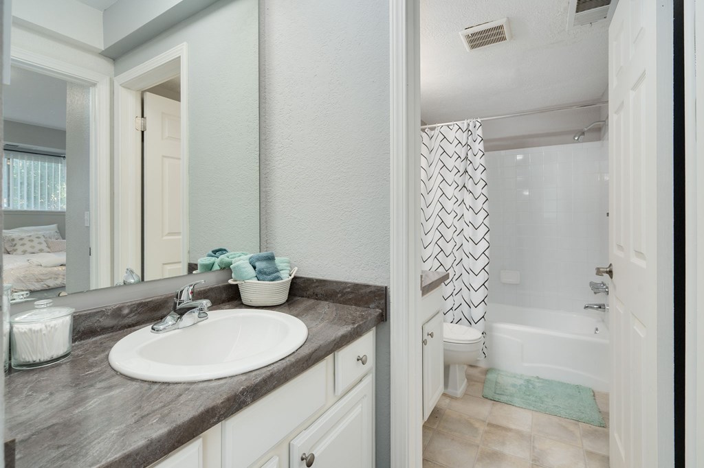A bathroom with a sink, mirror, and shower.