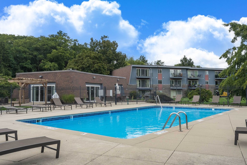 A swimming pool with a bench and a building in the background.