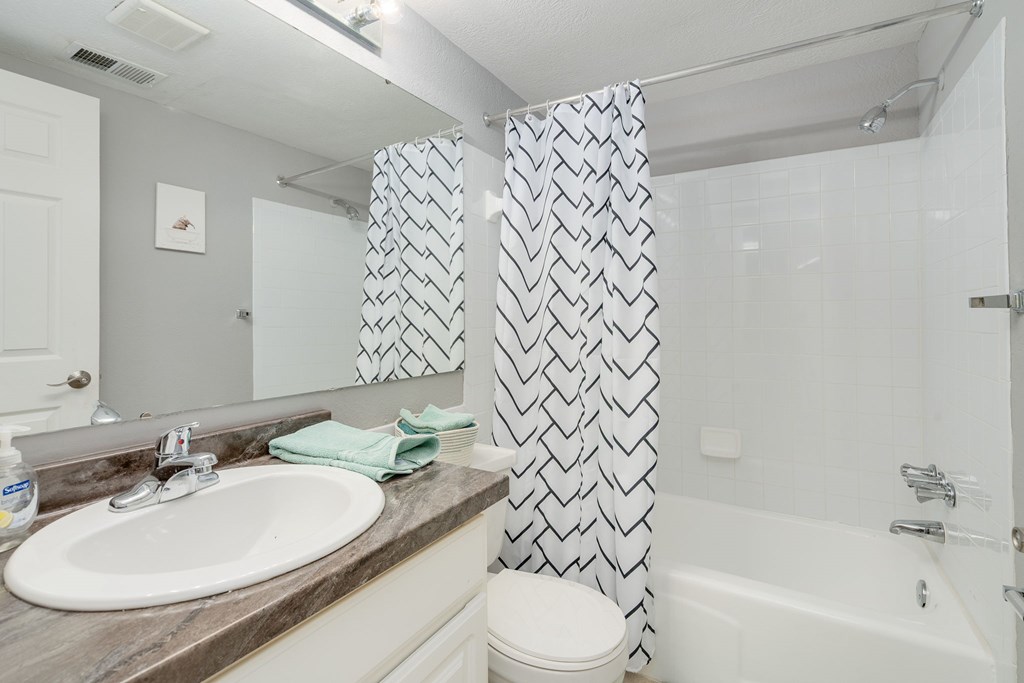 A bathroom with a white sink and a shower curtain with a black and white pattern.