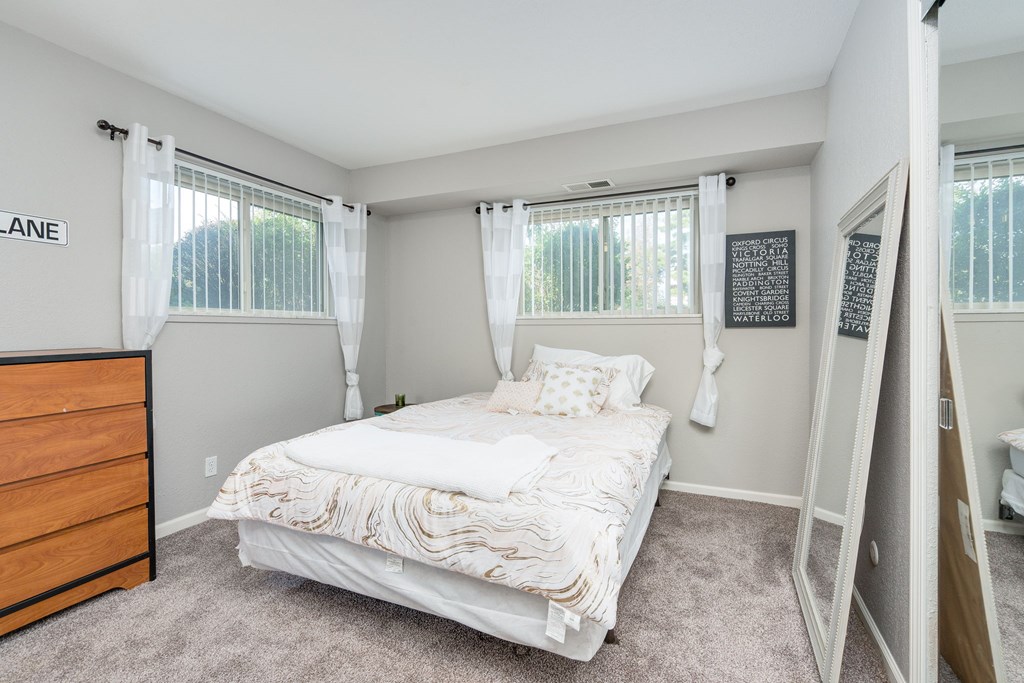 A bedroom with a bed, dresser, and mirror.
