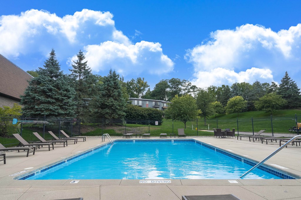 A large swimming pool surrounded by trees and a fence.