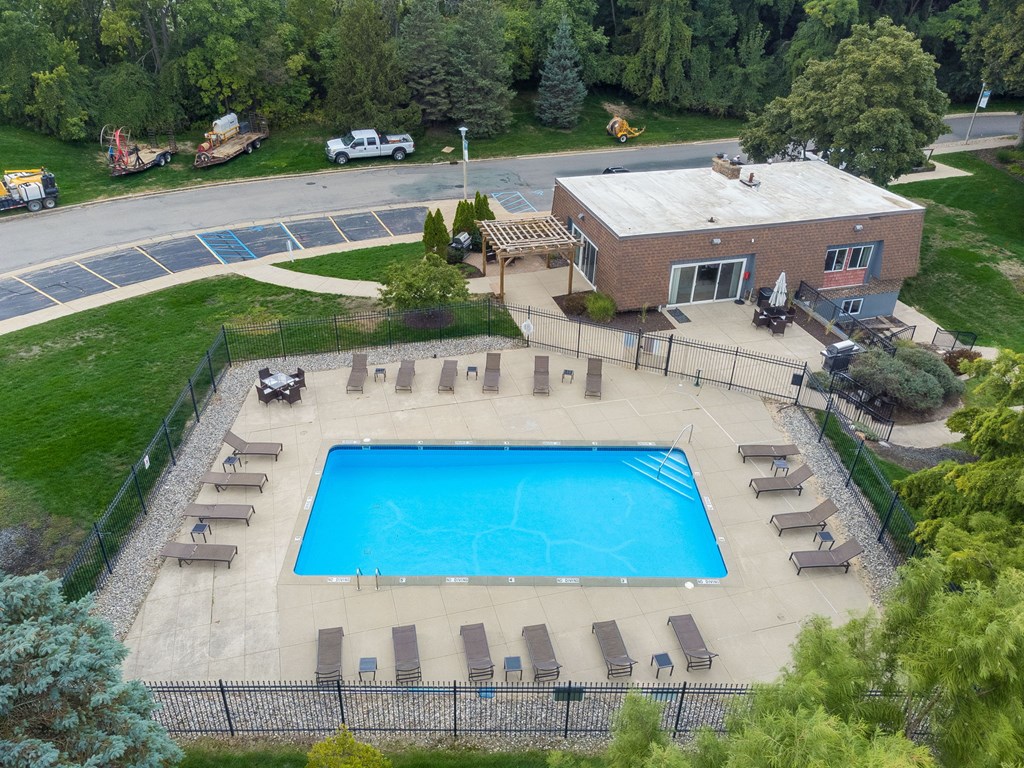 A large swimming pool surrounded by a fence and lounge chairs.