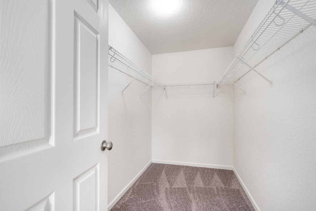 A white door is on the left of a hallway with a carpeted floor.