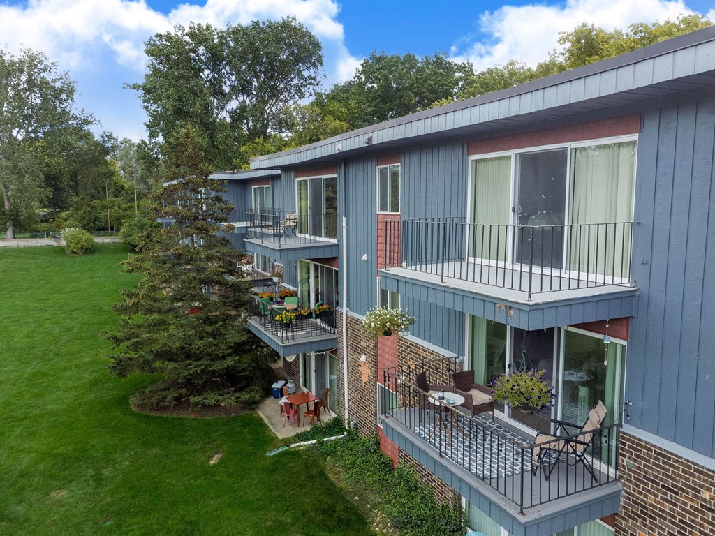 A balcony with chairs and a table is on the second floor of a building.