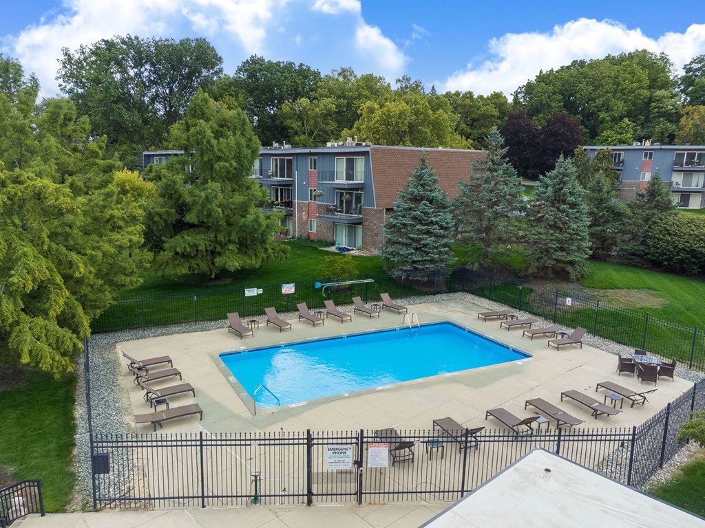 A pool surrounded by trees and chairs.
