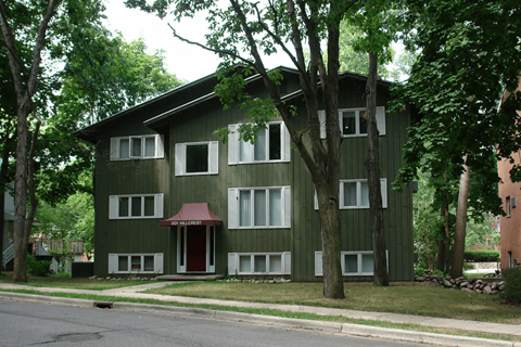 A green building with a red awning sits on a street.