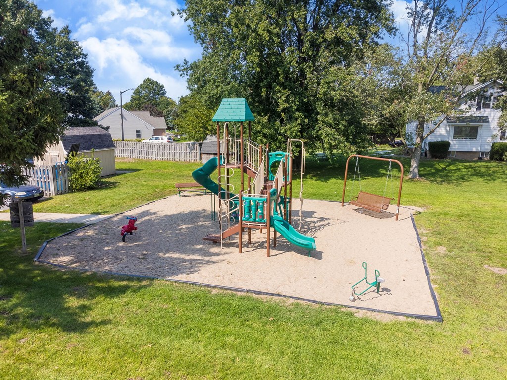 A playground with a green slide and a red toy car.