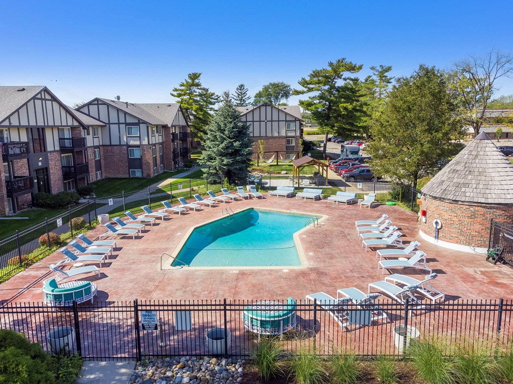 A pool surrounded by chairs and trees in front of apartment buildings.