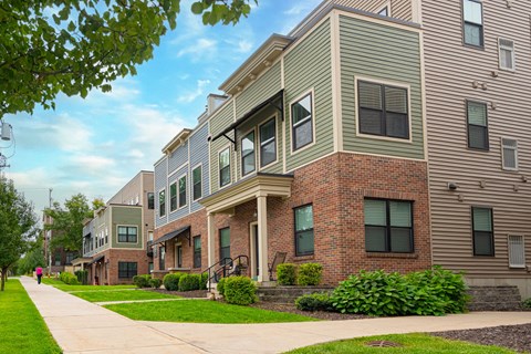 A row of modern townhouses with green lawns and trees.