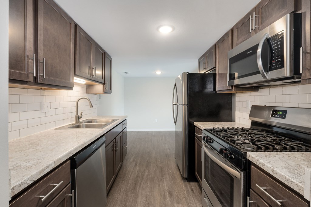 A modern kitchen with dark wood cabinets and stainless steel appliances.