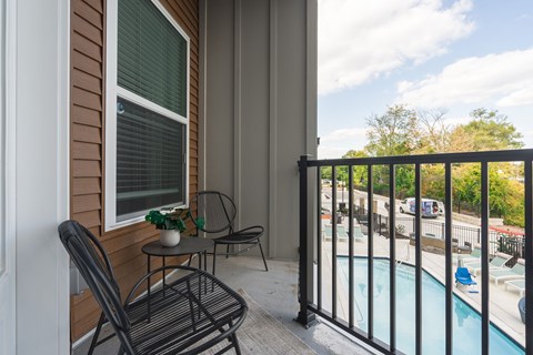 A balcony with a table and chairs overlooking a pool.