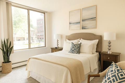 A bedroom with a large bed and a potted plant.