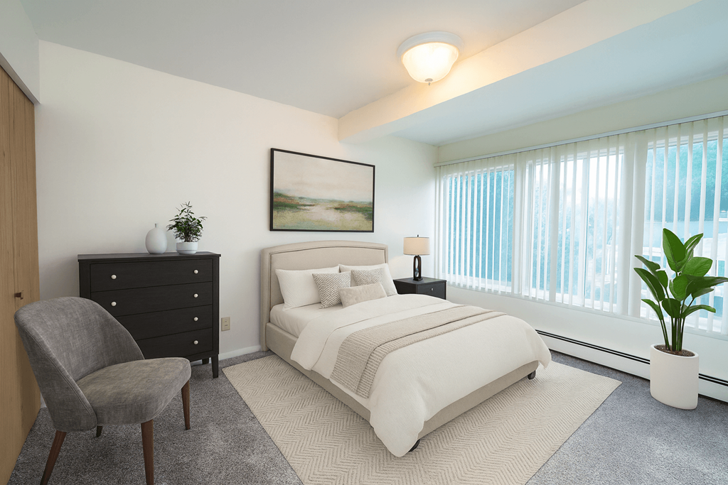 A bedroom with a large bed, a chair, and a painting on the wall.