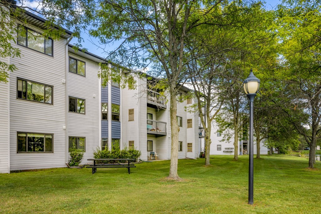a large white apartment building with a lawn and trees