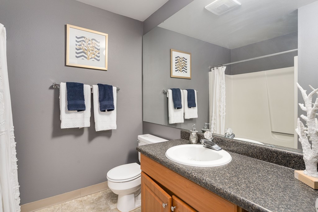 A bathroom with a toilet, sink, and towels.