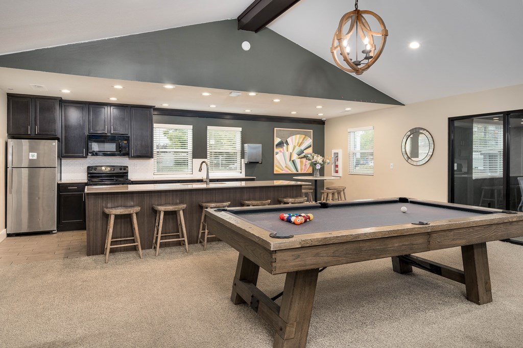 A pool table is in the middle of a kitchen and dining area.