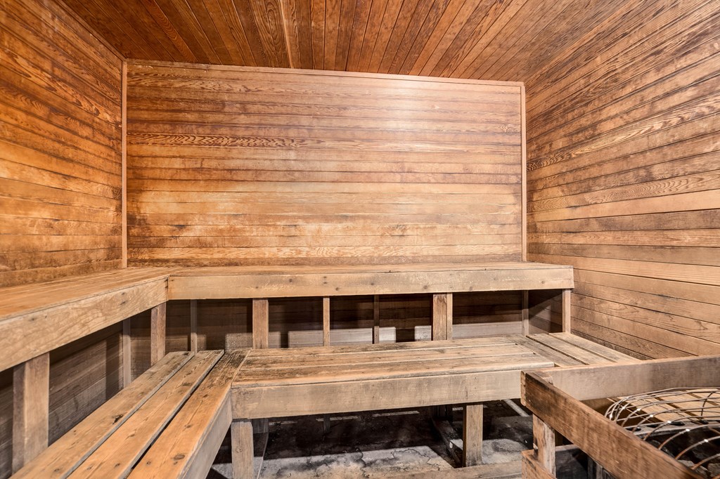 A wooden sauna with benches and a stone base.