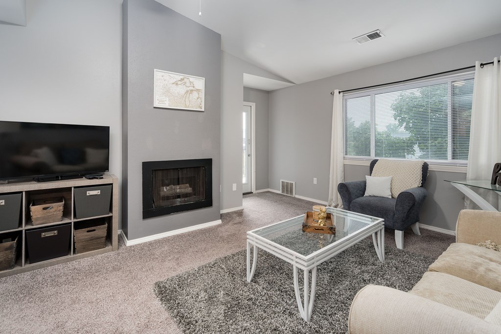 A living room with a fireplace and a glass coffee table.