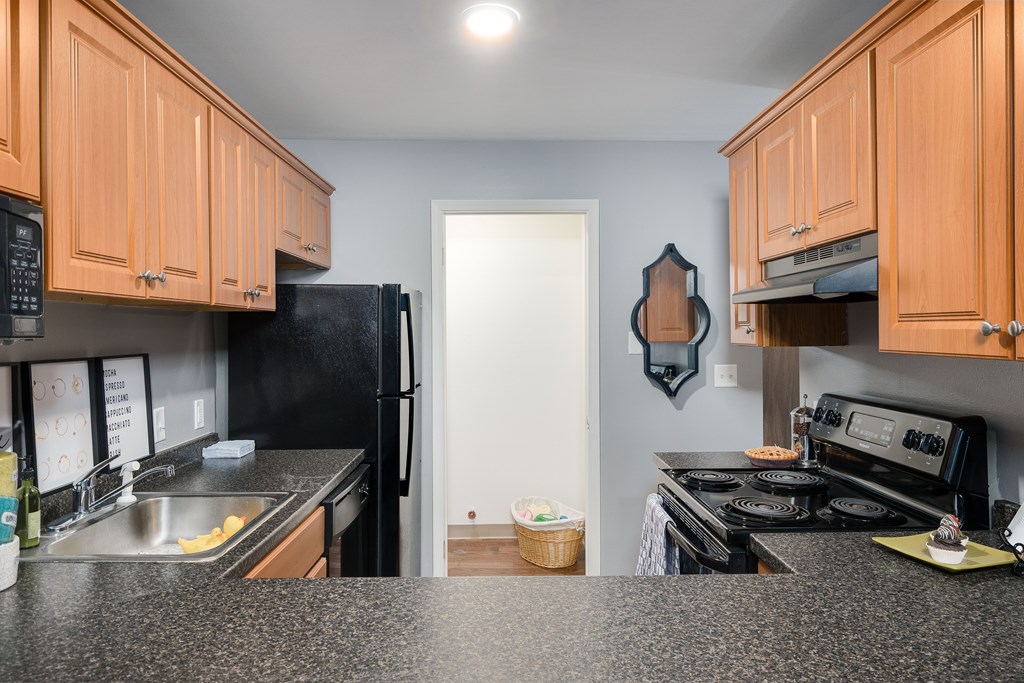 A kitchen with black appliances and wooden cabinets.