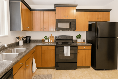 A kitchen with wooden cabinets and black appliances.