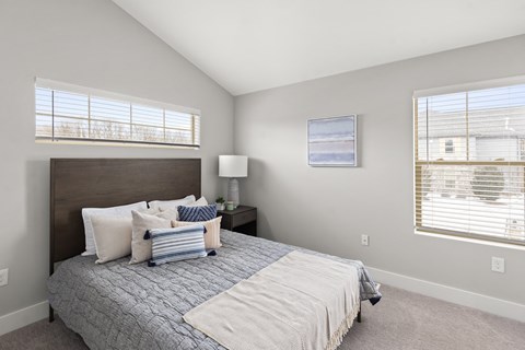 a bedroom with a large bed and two windows