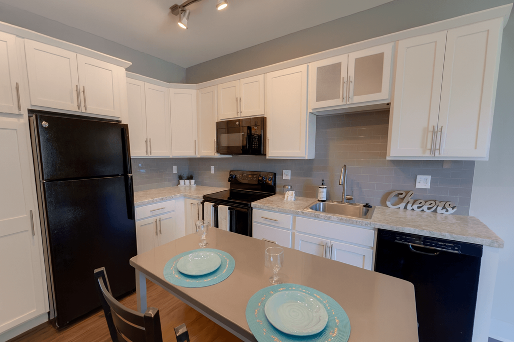 A kitchen with a table set for two with a plate and a glass.