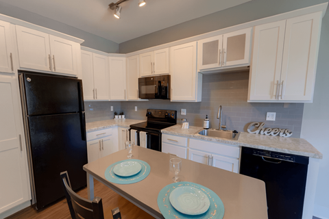 A kitchen with a table set for two with a plate and a glass.