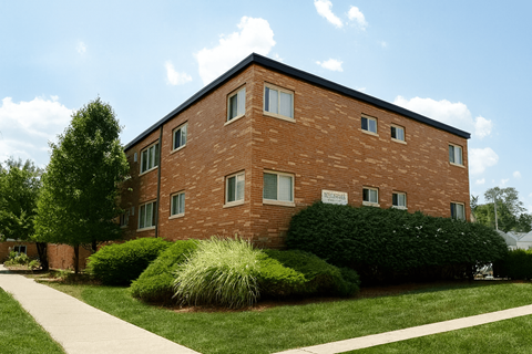 A red brick building with a green bush in front.